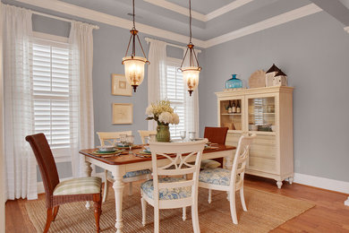 This is an example of a large beach style dining room in Charlotte with blue walls, light hardwood floors and no fireplace.