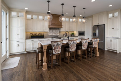 Large transitional l-shaped open plan kitchen in Kansas City with white cabinets, marble benchtops, multi-coloured splashback, ceramic splashback, stainless steel appliances, with island, brown floor, an undermount sink, raised-panel cabinets, dark hardwood floors and grey benchtop.