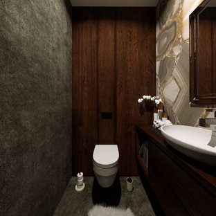 Ispirazione per un piccolo bagno di servizio contemporaneo con ante lisce, ante in legno bruno, WC sospeso, piastrelle marroni, piastrelle effetto legno, pareti grigie, pavimento in gres porcellanato, lavabo a bacinella, top in legno, pavimento nero, top marrone, mobile bagno sospeso e boiserie