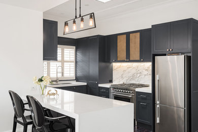 Inspiration for a mid-sized traditional u-shaped eat-in kitchen in Sydney with a double-bowl sink, shaker cabinets, black cabinets, marble benchtops, white splashback, marble splashback, stainless steel appliances, dark hardwood floors, with island, brown floor and white benchtop.