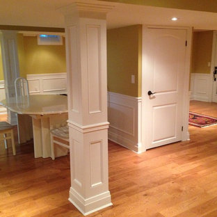 This is an example of a classic look-out basement in Toronto with yellow walls, light hardwood flooring, no fireplace and beige floors.