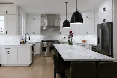 Large trendy galley medium tone wood floor and beige floor open concept kitchen photo in DC Metro with a drop-in sink, beaded inset cabinets, white cabinets, granite countertops, white backsplash, ceramic backsplash, black appliances, an island and white countertops