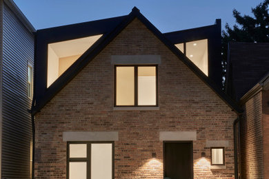 Diseño de fachada de casa marrón y negra retro de tamaño medio a niveles con revestimiento de ladrillo y tejado de metal