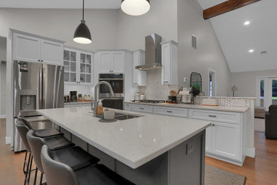 Mid-sized transitional l-shaped open concept kitchen photo in Other with flat-panel cabinets, white cabinets, quartz countertops, gray backsplash, an island and white countertops