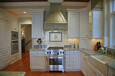 Elegant dark wood floor kitchen photo in Milwaukee with a farmhouse sink, recessed-panel cabinets, white cabinets, ceramic backsplash and paneled appliances