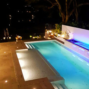 Foto di una grande piscina monocorsia design rettangolare dietro casa con fontane e pavimentazioni in cemento