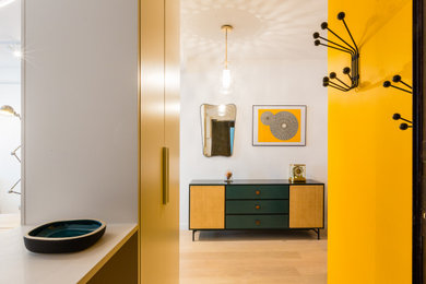 Idée de décoration pour une entrée design avec un vestiaire, un mur jaune, parquet clair, une porte simple, un sol beige et du papier peint.