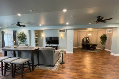 Large trendy laminate floor, brown floor and wallpaper basement photo in Baltimore with green walls