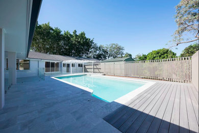 This is an example of a mid-sized contemporary backyard rectangular lap pool in Brisbane with concrete pavers.