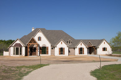 Example of a large mountain style white two-story stucco house exterior design in Dallas with a hip roof and a shingle roof