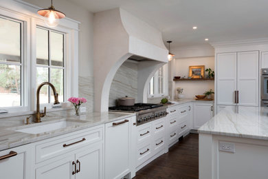 Eat-in kitchen - mid-sized coastal u-shaped medium tone wood floor, brown floor and tray ceiling eat-in kitchen idea in Denver with a drop-in sink, flat-panel cabinets, white cabinets, white backsplash, stainless steel appliances, an island and white countertops
