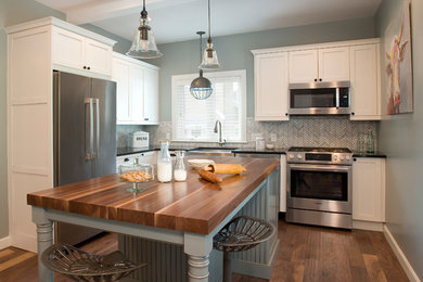 Inspiration for a mid-sized cottage l-shaped medium tone wood floor and brown floor eat-in kitchen remodel in Boston with a farmhouse sink, shaker cabinets, white cabinets, wood countertops, gray backsplash, marble backsplash, stainless steel appliances and an island