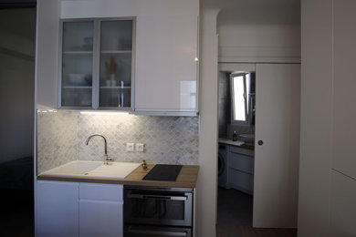 Réalisation d'une petite cuisine ouverte parallèle minimaliste avec des portes de placard blanches, aucun îlot et un plan de travail marron.