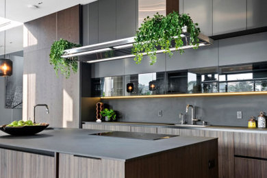 Inspiration for a large modern l-shaped eat-in kitchen remodel in Miami with a drop-in sink, flat-panel cabinets, medium tone wood cabinets, quartz countertops, gray backsplash, quartz backsplash, an island and gray countertops