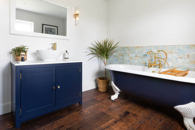 Inspiration for a large classic family bathroom in Oxfordshire with shaker cabinets, blue cabinets, a claw-foot bath, a corner shower, a two-piece toilet, blue tiles, ceramic tiles, white walls, vinyl flooring, a vessel sink, quartz worktops, brown floors, a sliding door, white worktops, a feature wall, a single sink and a freestanding vanity unit.