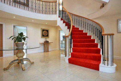 Large classic wood curved metal railing staircase in Other with painted wood risers.