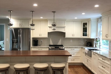 Design ideas for a mid-sized transitional l-shaped eat-in kitchen in Boston with a farmhouse sink, recessed-panel cabinets, white cabinets, quartz benchtops, beige splashback, ceramic splashback, stainless steel appliances, dark hardwood floors, with island and beige benchtop.