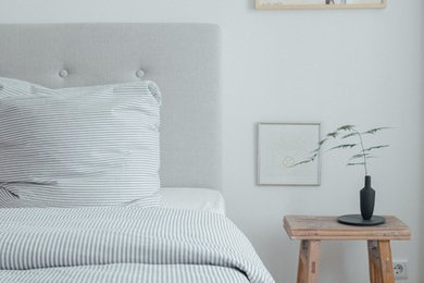 Mittelgroßes Nordisches Hauptschlafzimmer ohne Kamin mit weißer Wandfarbe, braunem Holzboden und braunem Boden in Berlin