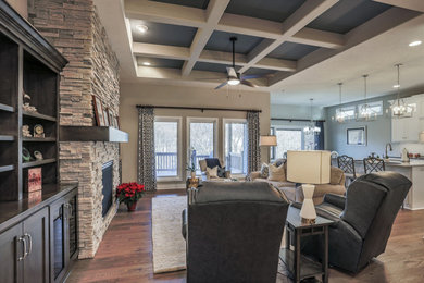 Inspiration for a large transitional open concept dark wood floor living room remodel in Omaha with gray walls, a standard fireplace, a stone fireplace and a wall-mounted tv