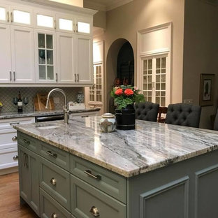 Große Klassische Küche in L-Form mit Vorratsschrank, Landhausspüle, Schrankfronten mit vertiefter Füllung, weißen Schränken, Granit-Arbeitsplatte, Küchenrückwand in Weiß, Rückwand aus Porzellanfliesen, Küchengeräten aus Edelstahl, braunem Holzboden, Kücheninsel und blauer Arbeitsplatte in Toronto