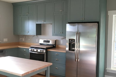 Mid-sized cottage u-shaped medium tone wood floor and brown floor eat-in kitchen photo in New York with a farmhouse sink, recessed-panel cabinets, blue cabinets, wood countertops, an island and brown countertops