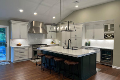 Eat-in kitchen - large transitional l-shaped medium tone wood floor, brown floor and vaulted ceiling eat-in kitchen idea in New York with an undermount sink, recessed-panel cabinets, white cabinets, quartz countertops, white backsplash, quartz backsplash, stainless steel appliances, an island and white countertops