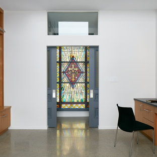 This is an example of an expansive modern home office and library in Ottawa with a reading nook, white walls, concrete flooring, no fireplace, a built-in desk and grey floors.