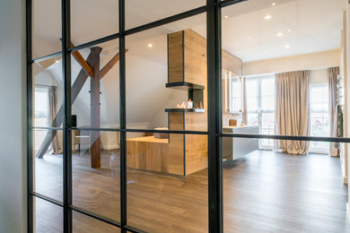 Großes Eklektisches Duschbad mit flächenbündigen Schrankfronten, grauen Schränken, Einbaubadewanne, Wandtoilette, weißer Wandfarbe, braunem Holzboden, Einbauwaschbecken und braunem Boden in Hannover