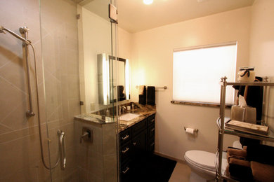 Corner shower - mid-sized transitional master beige tile and porcelain tile porcelain tile corner shower idea in Other with an undermount sink, recessed-panel cabinets, dark wood cabinets, granite countertops, a two-piece toilet and beige walls