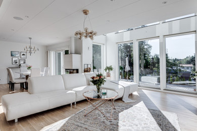 Imagen de salón con barra de bar abierto y beige y blanco nórdico grande de obra con paredes blancas, suelo de madera clara, chimenea de doble cara, marco de chimenea de hormigón, televisor colgado en la pared, suelo beige y bandeja