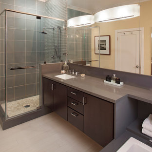 Ispirazione per una stanza da bagno padronale minimalista di medie dimensioni con ante lisce, ante in legno bruno, vasca da incasso, doccia ad angolo, piastrelle blu, piastrelle grigie, piastrelle di vetro, pareti gialle, pavimento in gres porcellanato, lavabo sottopiano e top in superficie solida