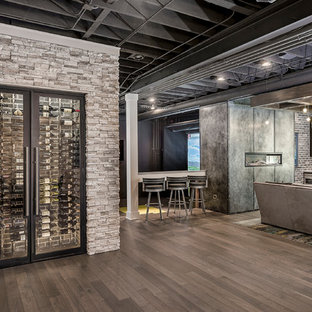 シカゴの大きいコンテンポラリースタイルのおしゃれな地下室 (全地下、ベージュの壁、無垢フローリング、横長型暖炉、金属の暖炉まわり、茶色い床) の写真