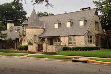 This is an example of a large midcentury two-storey beige house exterior in Dallas with stone veneer, a gable roof and a shingle roof.