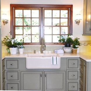 サンディエゴの中サイズのトラディショナルスタイルのおしゃれな家事室 (落し込みパネル扉のキャビネット、グレーのキャビネット、ライムストーンカウンター、白い壁、トラバーチンの床、左右配置の洗濯機・乾燥機、赤い床、エプロンフロントシンク) の写真