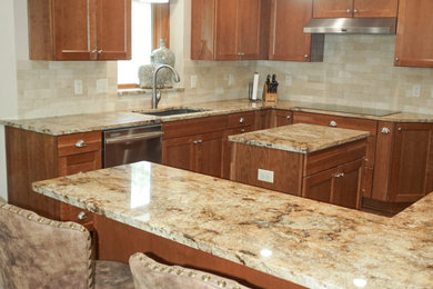 Example of a mid-sized u-shaped laminate floor enclosed kitchen design in Other with a double-bowl sink, recessed-panel cabinets, medium tone wood cabinets, granite countertops, beige backsplash, ceramic backsplash, stainless steel appliances and an island