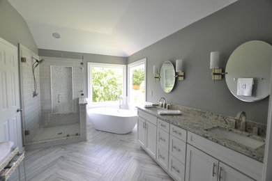 Inspiration for a mid-sized transitional master bathroom in Atlanta with shaker cabinets, white cabinets, a freestanding tub, a corner shower, a one-piece toilet, gray tile, porcelain tile, grey walls, porcelain floors, an undermount sink and limestone benchtops.