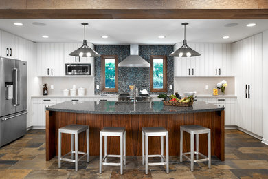 Inspiration for a large beach style kitchen in Minneapolis with an undermount sink, white cabinets, granite benchtops, multi-coloured splashback, mosaic tile splashback, stainless steel appliances, slate floors, with island and brown floor.