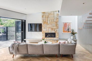 Inspiration for a large contemporary living room in Sydney with white walls, light hardwood floors, a standard fireplace, a stone fireplace surround and beige floor.