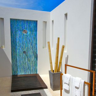 Diseño de cuarto de baño principal, exótico, de tamaño medio, con lavabo con pedestal, armarios con paneles lisos, puertas de armario de madera en tonos medios, encimera de madera, ducha abierta, sanitario de dos piezas, baldosas y/o azulejos azules, baldosas y/o azulejos de vidrio, paredes blancas y suelo de baldosas tipo guijarro