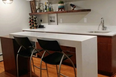 Example of a mid-sized 1960s single-wall laminate floor and brown floor wet bar design in Other with an undermount sink, flat-panel cabinets, dark wood cabinets, quartz countertops and white countertops