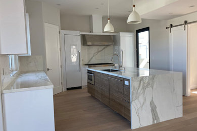 Eat-in kitchen - mid-sized modern light wood floor and beige floor eat-in kitchen idea in Los Angeles with an undermount sink, brown cabinets, quartz countertops, white backsplash, quartz backsplash, paneled appliances, an island and white countertops