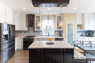 Large transitional l-shaped eat-in kitchen in San Francisco with a single-bowl sink, shaker cabinets, white cabinets, solid surface benchtops, multi-coloured splashback, with island and white benchtop.