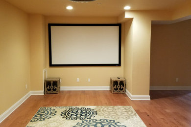 Inspiration for a mid-sized modern open concept medium tone wood floor and brown floor home theater remodel in Philadelphia with yellow walls and a projector screen