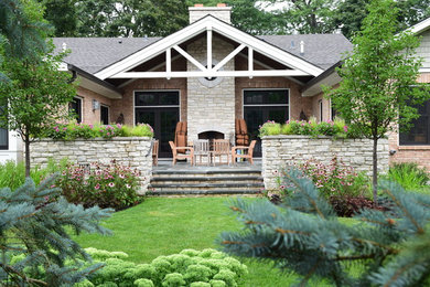 This is an example of a mid-sized traditional backyard partial sun garden for summer in Chicago with natural stone pavers and a retaining wall.