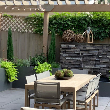 Hardscapes: stone patio with dining table, wall fountain, container plantings