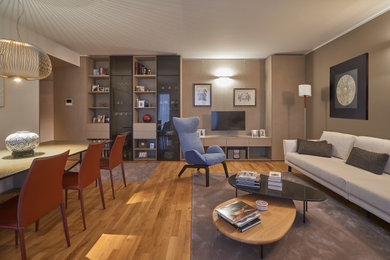 Immagine di un soggiorno contemporaneo di medie dimensioni e aperto con pareti beige, parquet chiaro, parete attrezzata, pannellatura e con abbinamento di mobili antichi e moderni