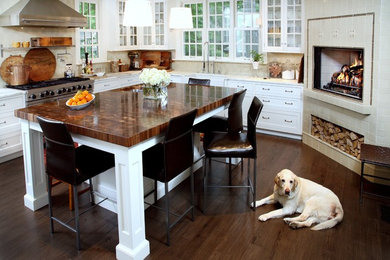 Inspiration for a timeless dark wood floor kitchen remodel in New York with a farmhouse sink, white cabinets, beige backsplash, stainless steel appliances and an island