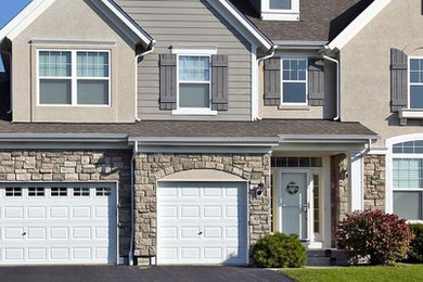 Example of a mid-sized transitional beige two-story stone house exterior design in New York with a clipped gable roof and a shingle roof