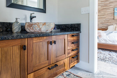 Large contemporary master bathroom in Austin with shaker cabinets, medium wood cabinets, a freestanding tub, a corner shower, gray tile, marble, beige walls, marble floors, a vessel sink, granite benchtops, beige floor, a hinged shower door and black benchtops.