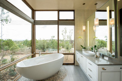 Example of a large transitional porcelain tile and gray floor freestanding bathtub design in Albuquerque with flat-panel cabinets, white cabinets, beige walls and a vessel sink